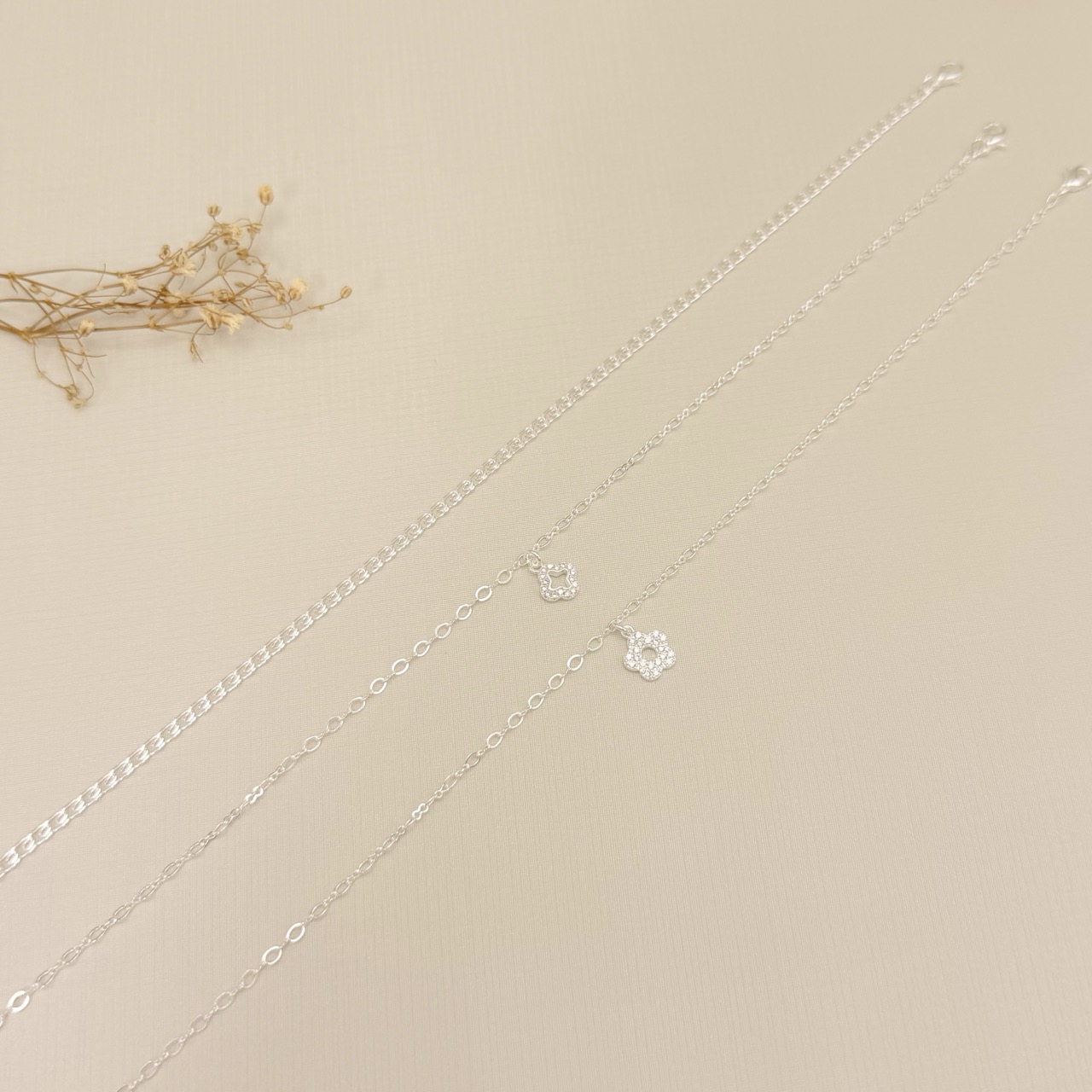 14.0336.1.S - Tornozeleira com pingente de silhueta de flor alhambra cravejada, insp. Van-Cleef, malha elo oval e elo infinito.