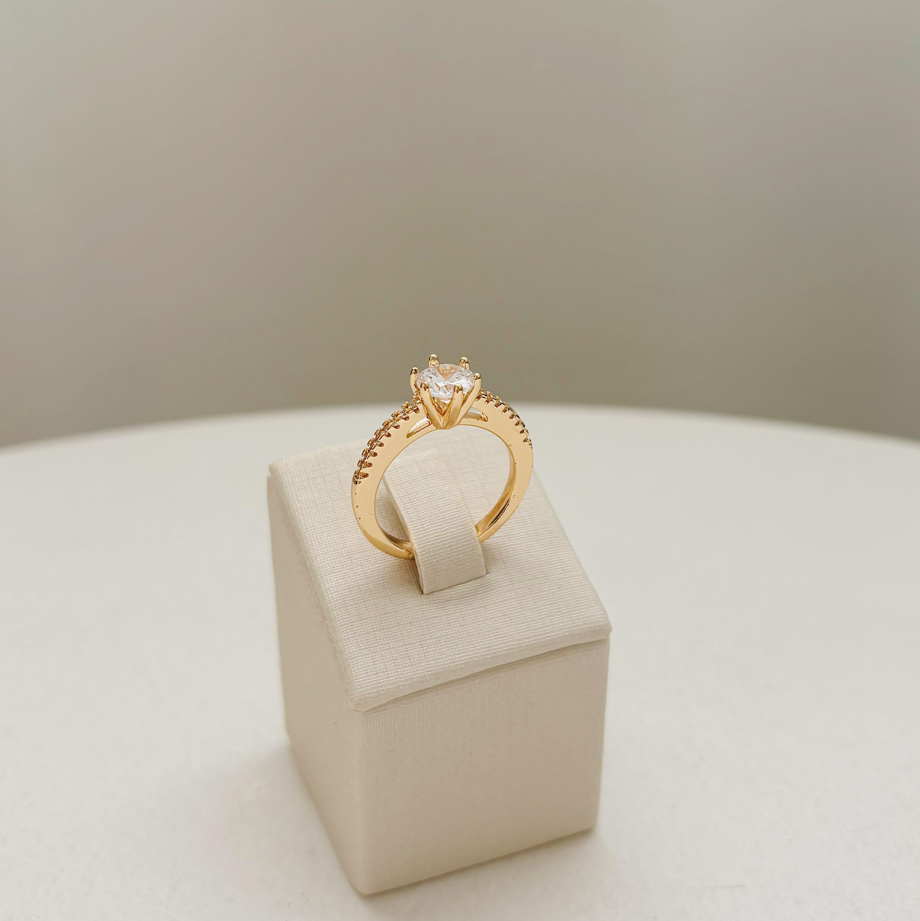 ANEL SOLITÁRIO ALTO. ZIRCÔNIA 6MM COM CRAVEJADO LATERAL. TAMANHO 19. BANHADO A OURO 18K.