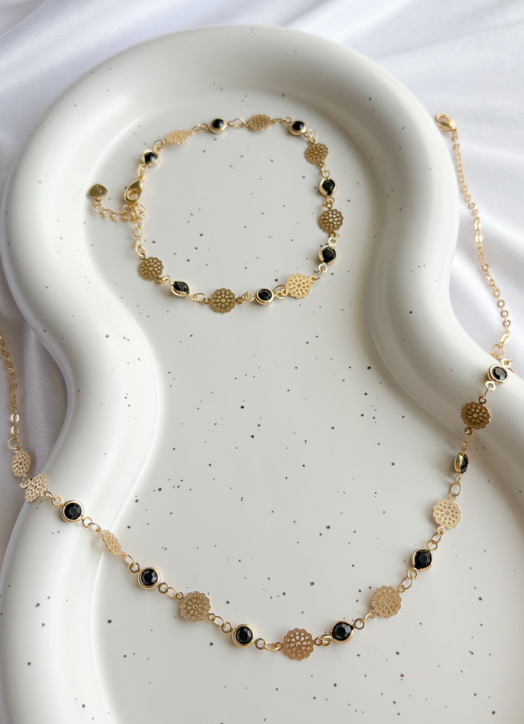 PULSEIRA MEDALHAS FLORES E PEDRAS PRETAS B. OURO