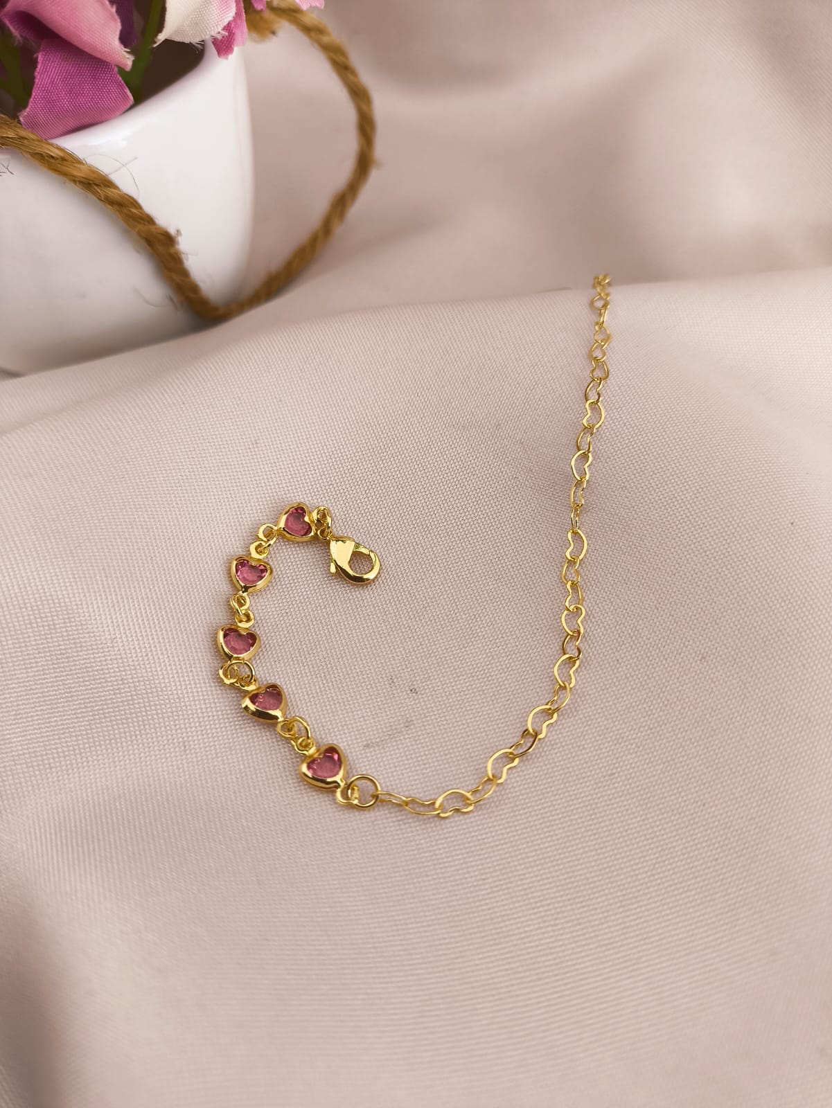 PULSEIRA INFANTIL MEIA CORAÇÃO ENTRELAÇADOS E MEIA PEDRAS DE CORAÇÕES ROSAS
